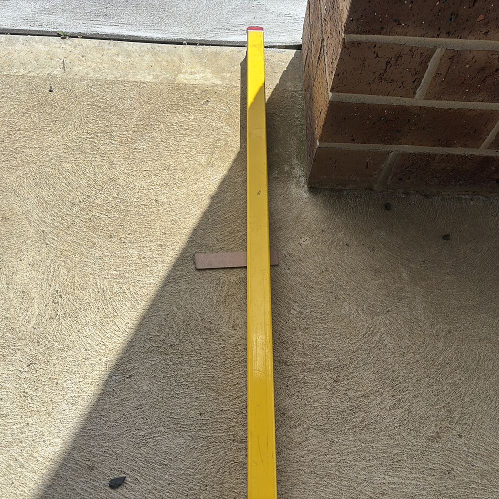 Uneven concrete causing ponding at a brick pier, recorded on a defect investigation in Winter Valley